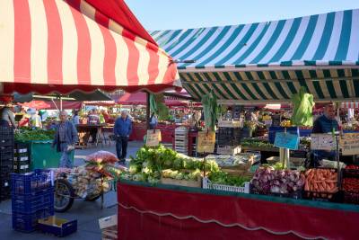 photo from the middle of a market with temporary stalls and striped fabric awnings